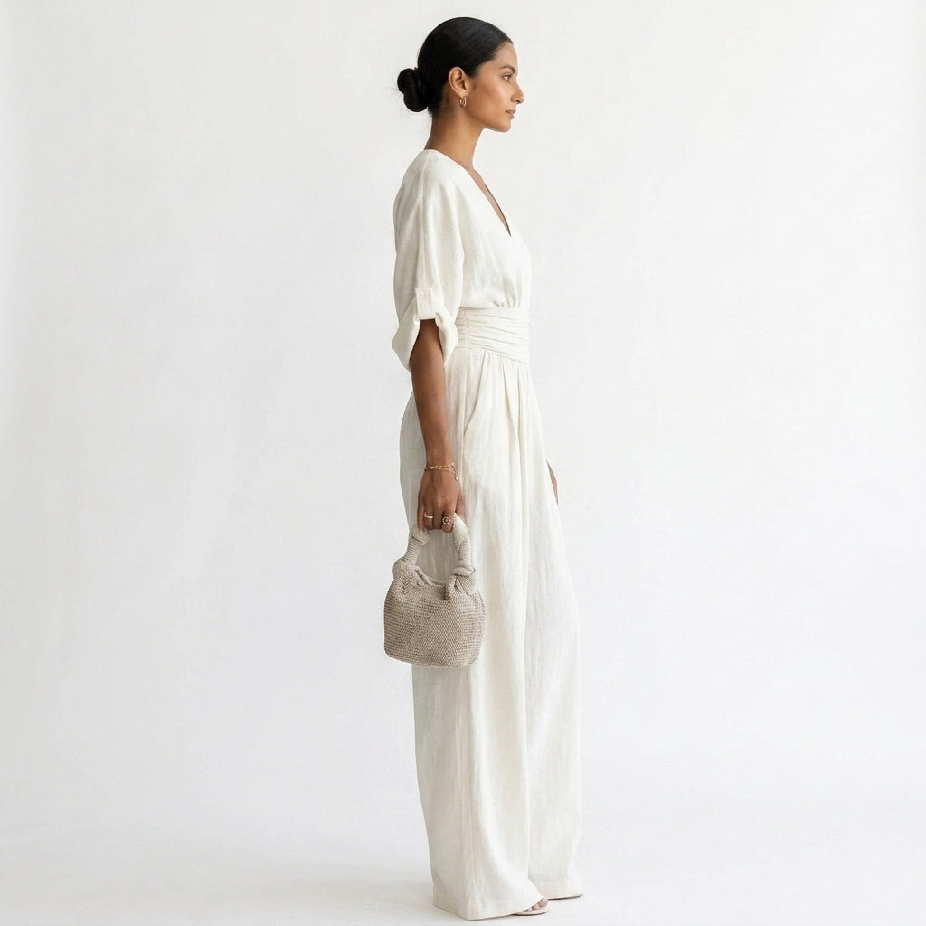 White wide-leg jumpsuit with deep V neckline, draped sleeves, and elastic waistband