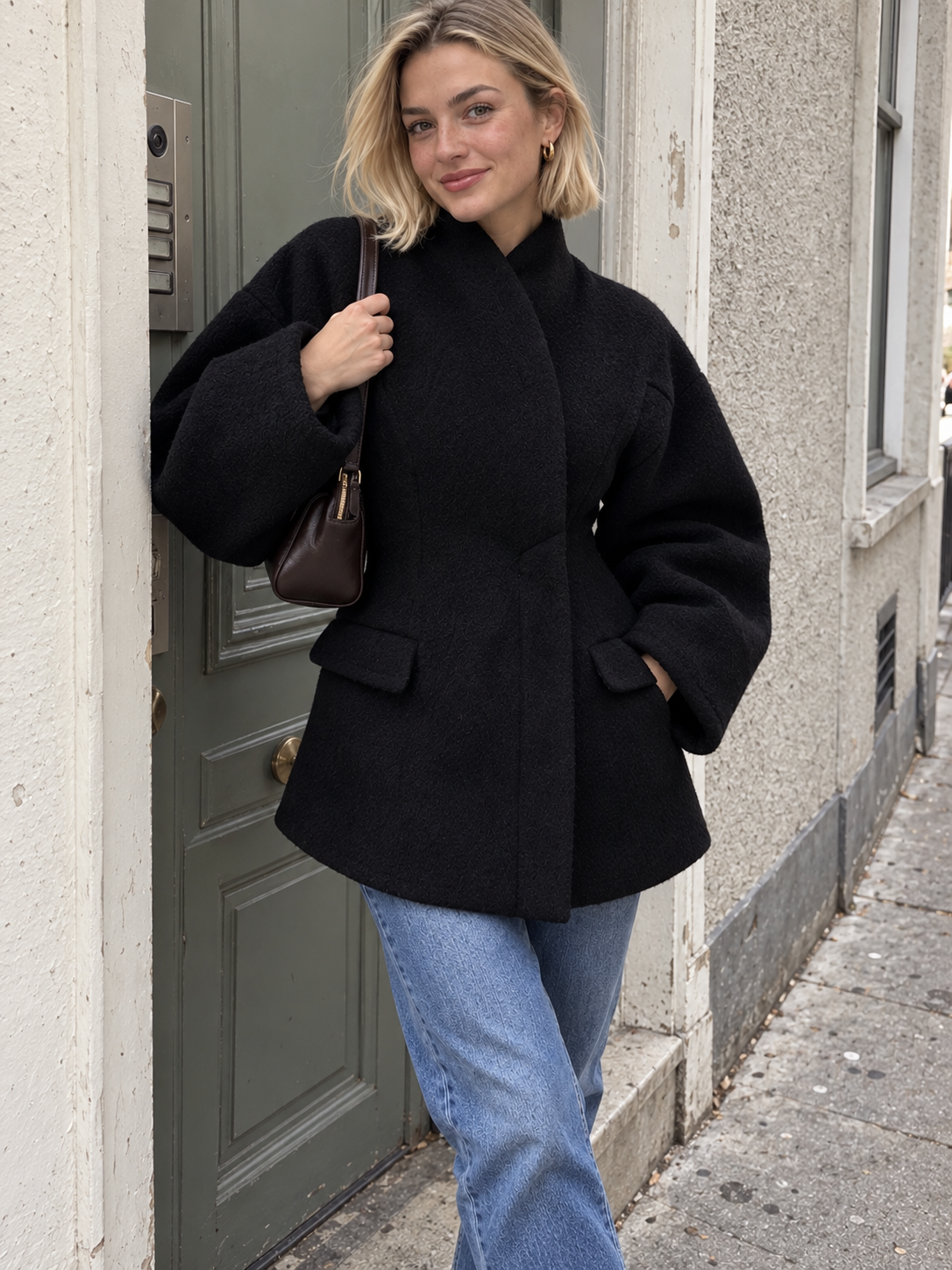 Black wool coat with raised collar, flap pockets, and long sleeves