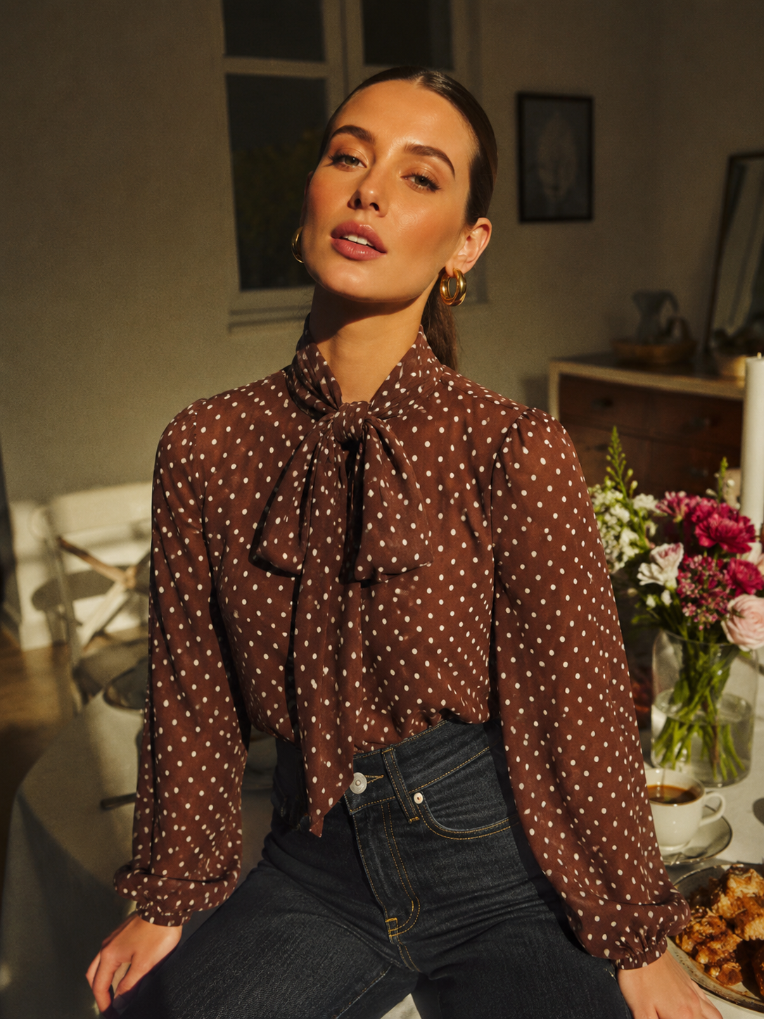 Dark polka dot tie-neck blouse with long sleeves and neck bow, flowing silhouette.