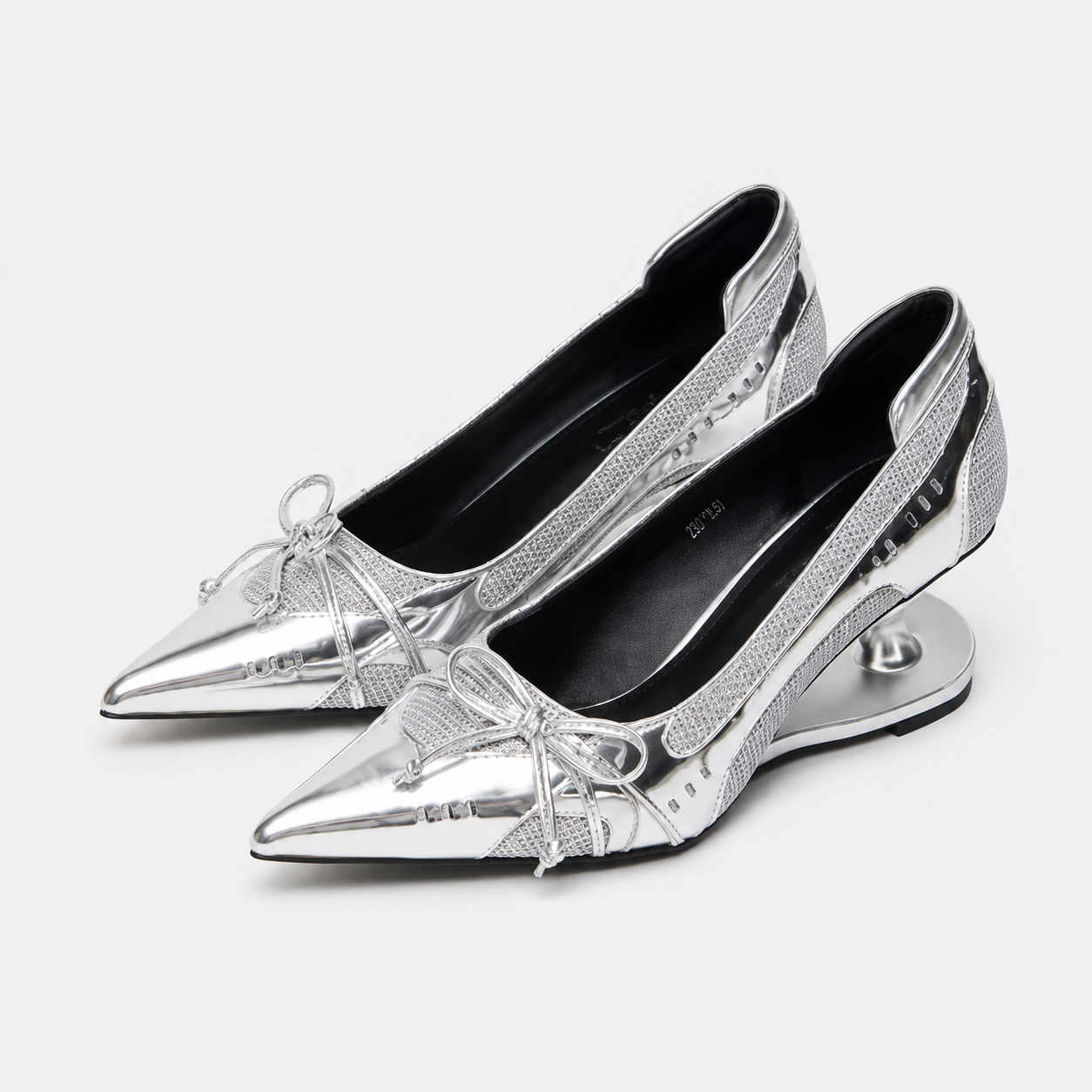 Silver metallic Mary Jane pumps with pointed toe, lace bow, and low sculpted heel