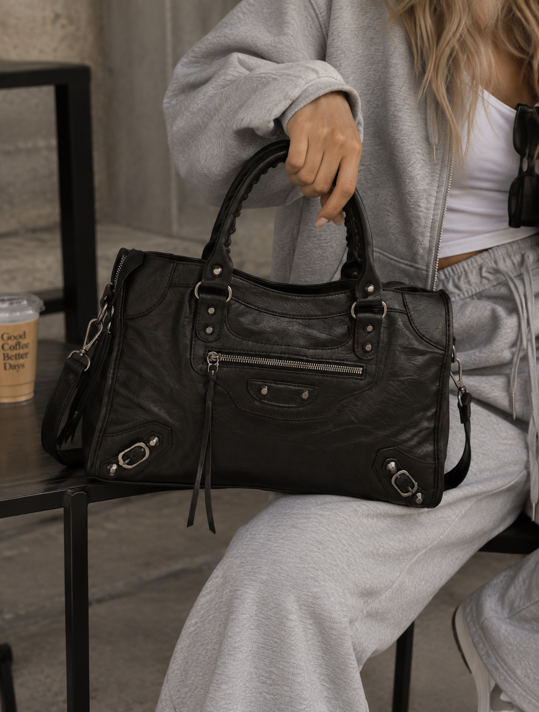 Black leather motorcycle crossbody tote with top handles, zipper pocket, and strap