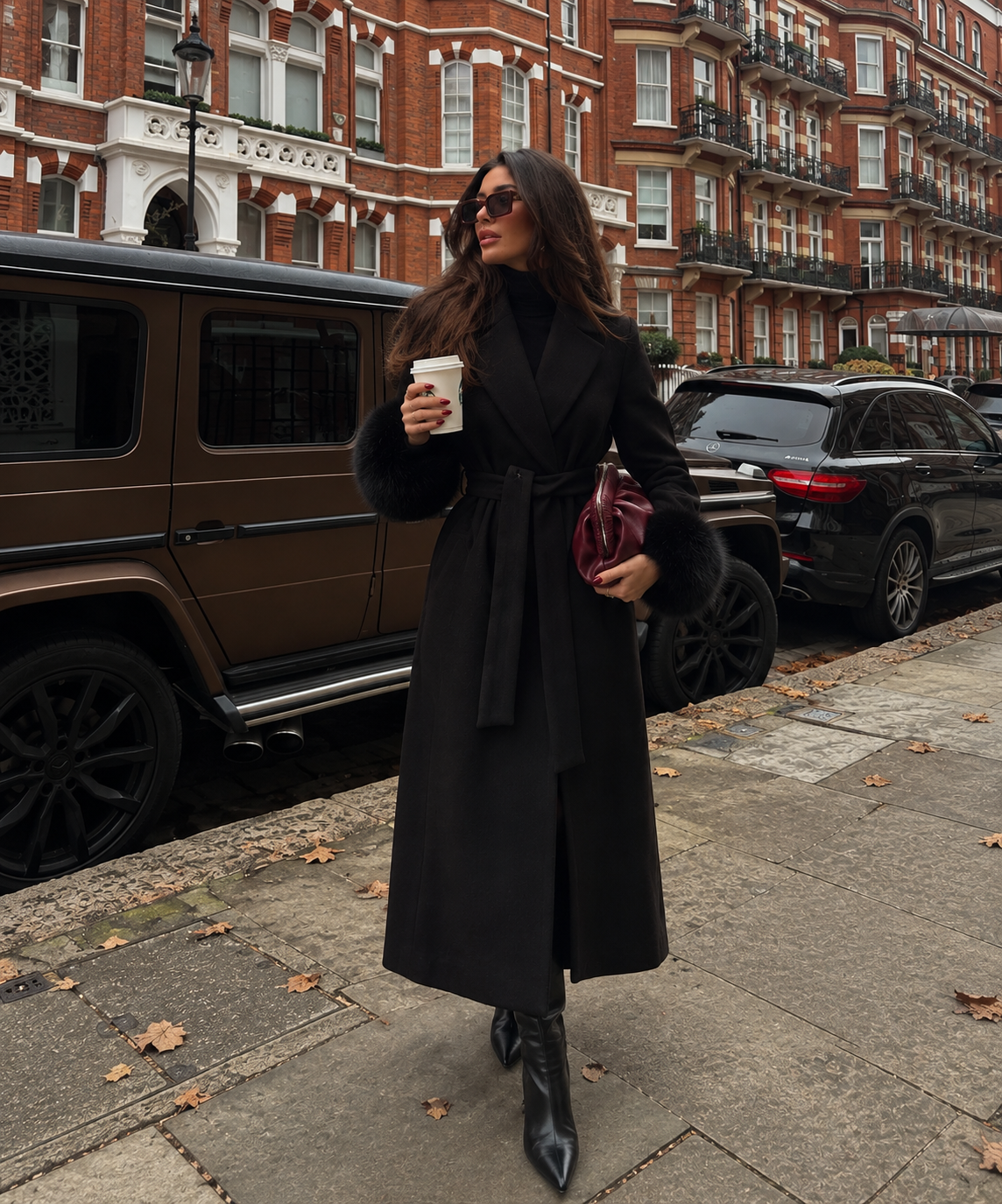 Black long wool coat with fur-trim cuffs, wrap belt, and pointed lapels