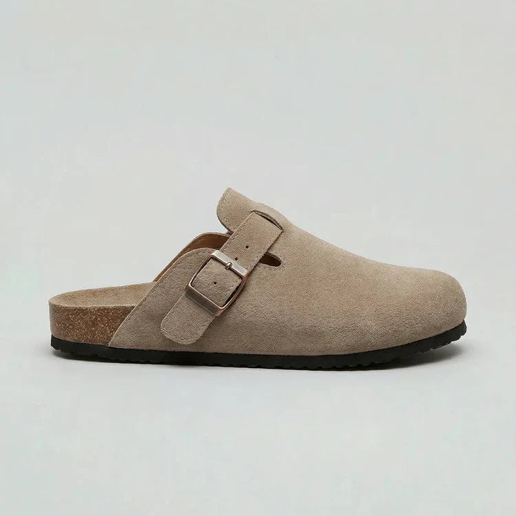Suede buckle clog in light sand with adjustable metal strap and dark rubber sole.