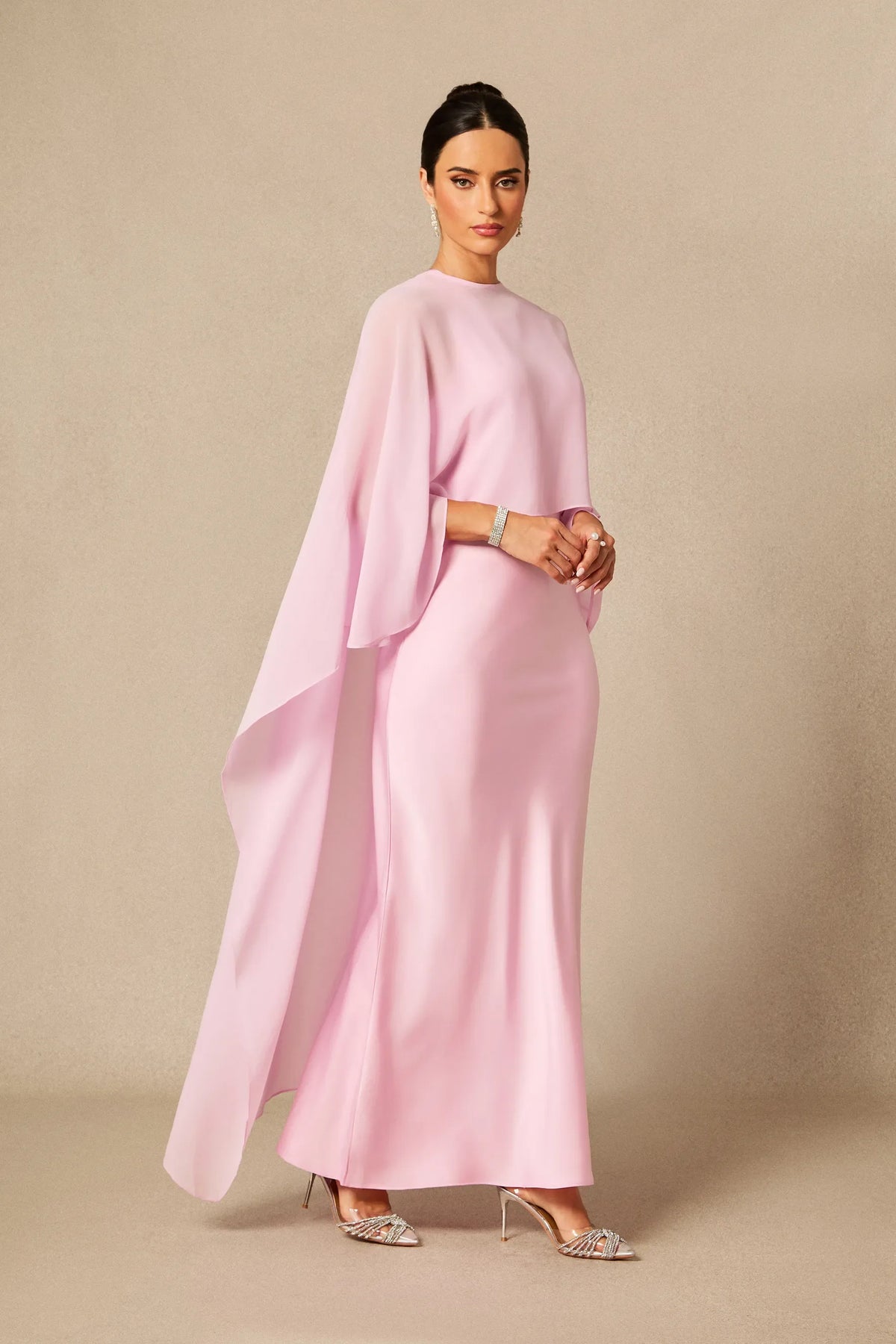 Pink women's maxi dress with batwing cape sleeves, draped overlay, and fitted waist