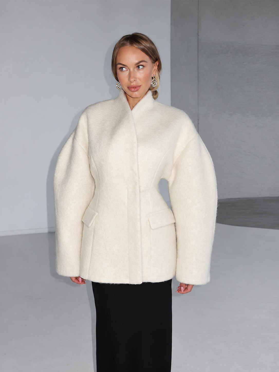 White wool coat with raised collar, long sleeves, and flap pockets