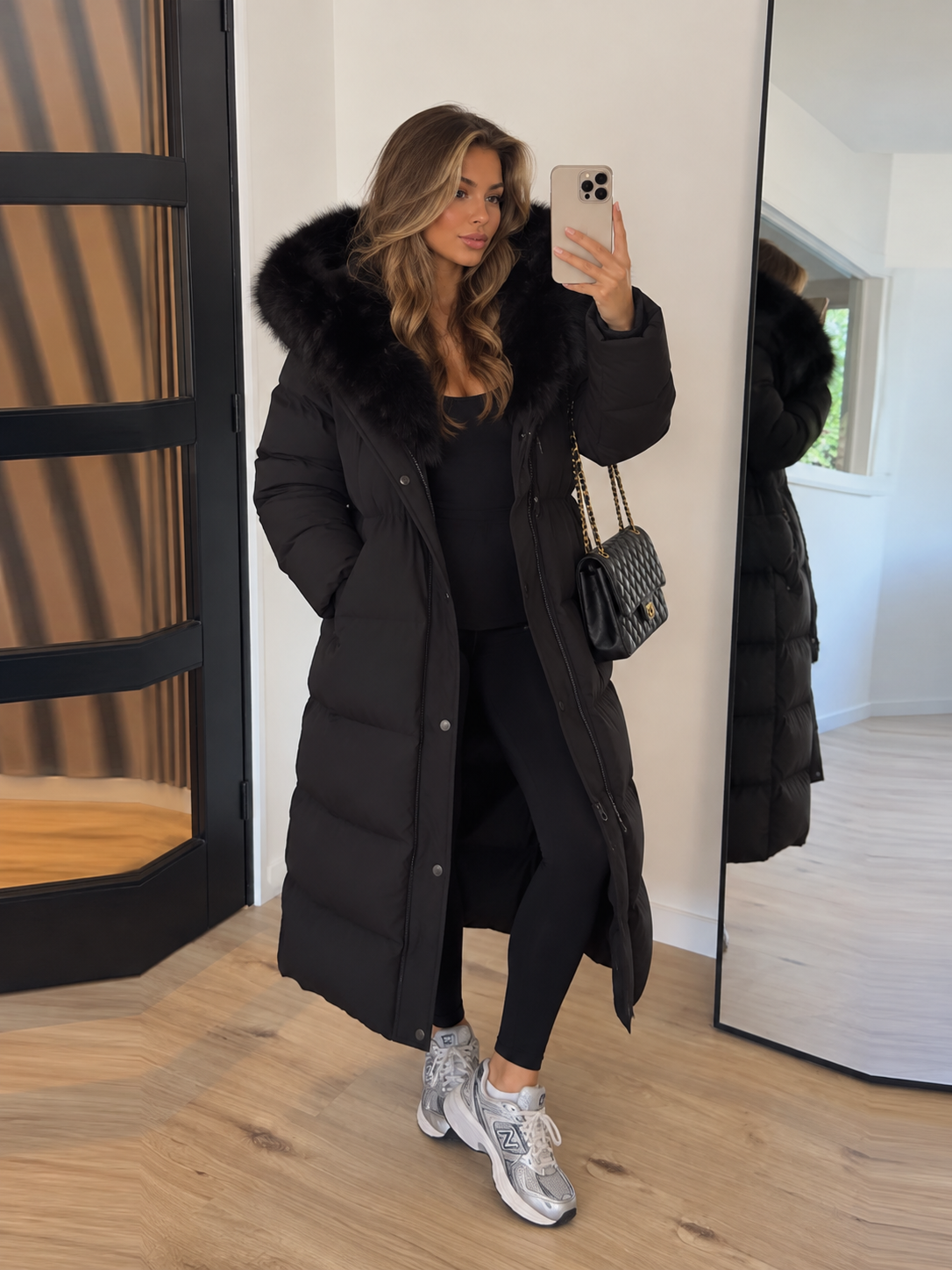 Black long puffer coat with faux-fur hood, button front, and tied waist drawstring