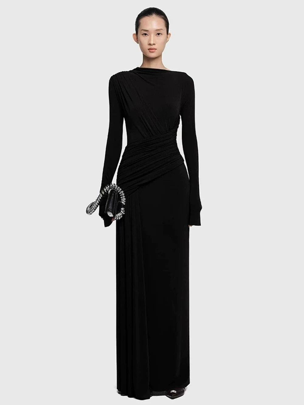 Black diagonal-collar pleated slim maxi dress with ruched waist and long sleeves