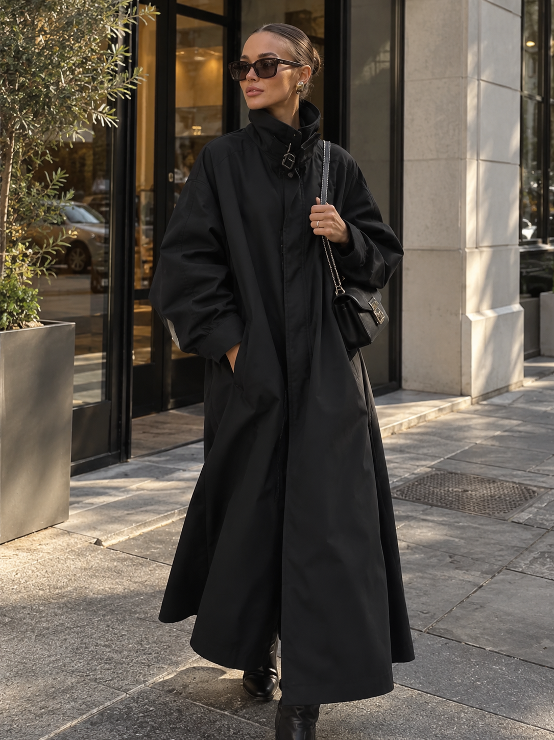 Black lace-up funnel neck trench coat with voluminous sleeves and tie collar