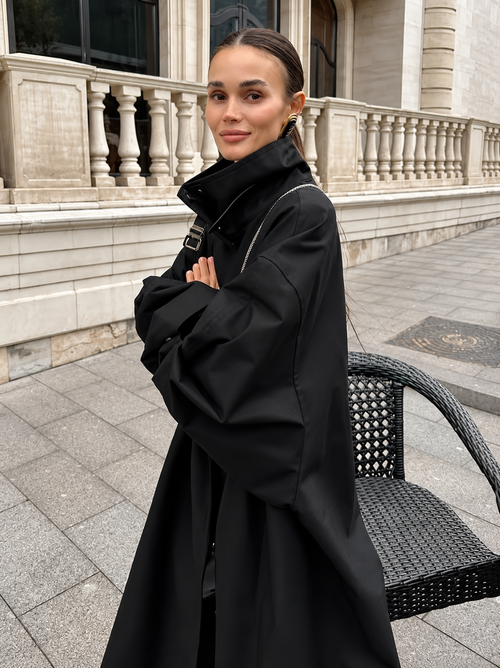 Black trench coat with lace-up funnel neck and draped, wide sleeves