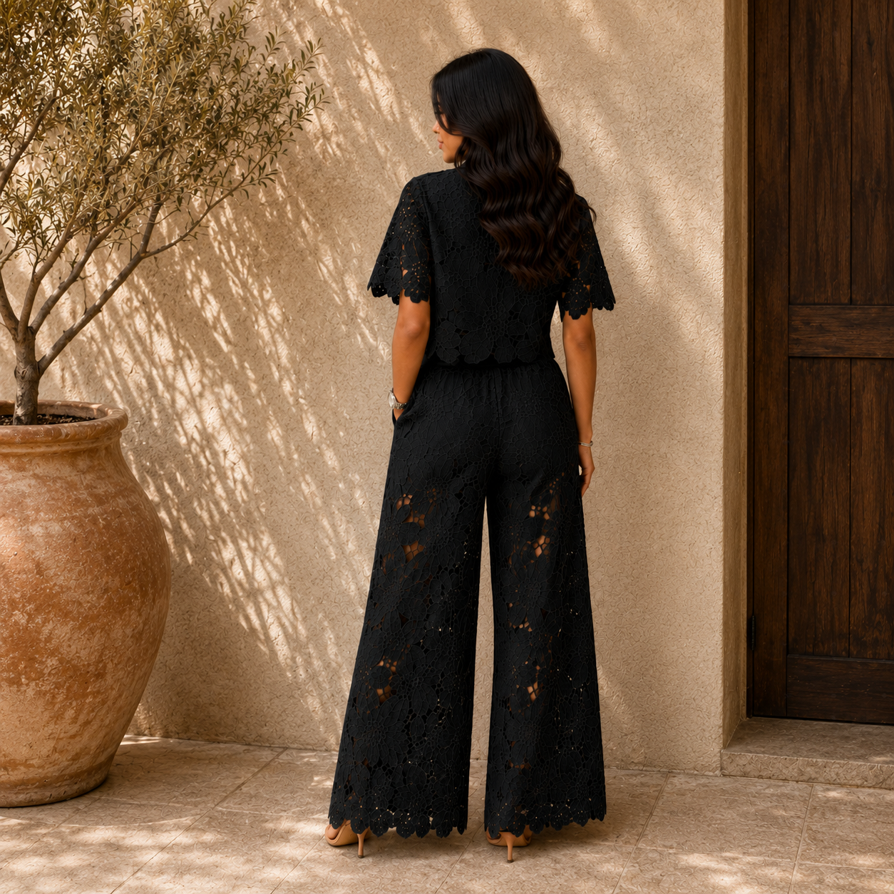Back view of black lace two-piece set: short-sleeve blouse and wide-leg pants.